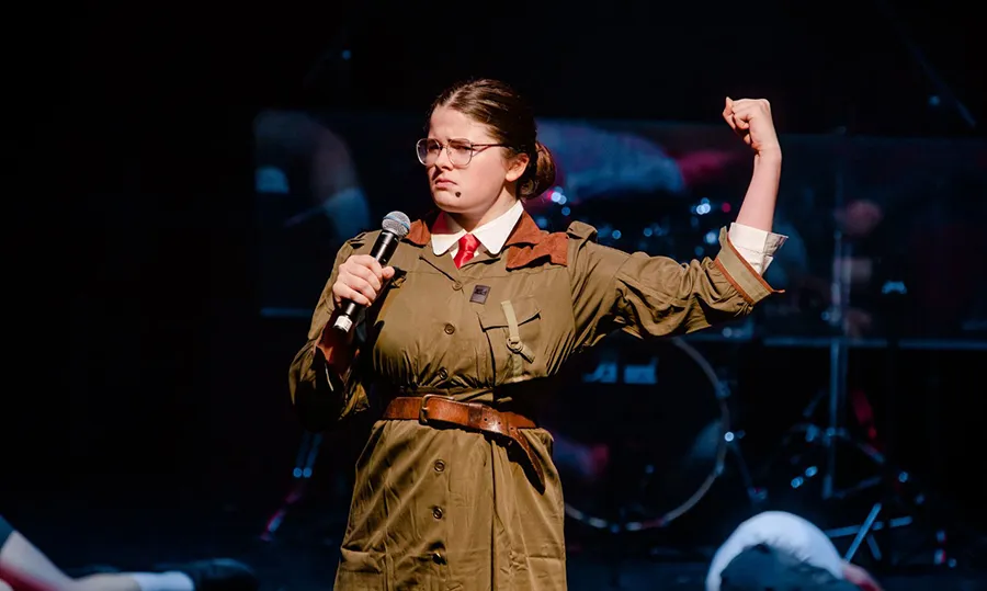 A student from St John Payne School on stage performing in a scene from Matilda. Photo by Aaron Crowe.