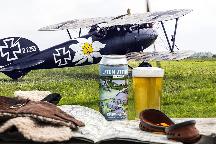 Can and glass of Datum Attitude Brewery with an old aeroplane in the background
