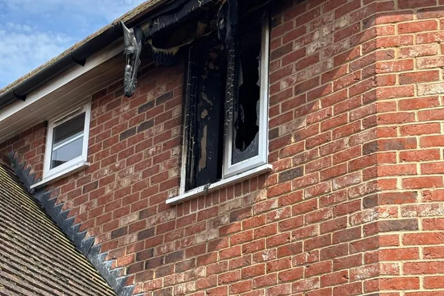 Broken window and melted window frame and guttering following the house fire