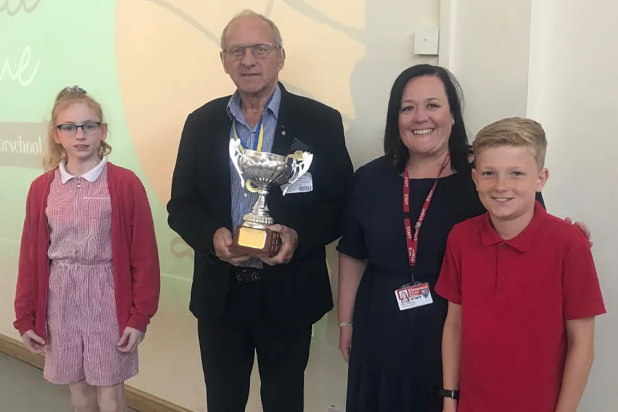 Terry Tilbrook presenting the cup to Elmwood Primary School staff member and two pupils