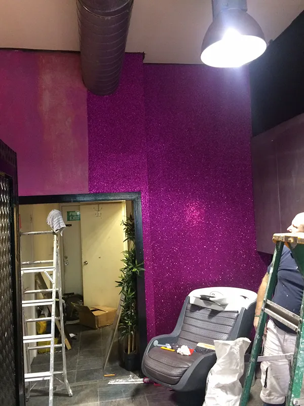 Decorating with purple glittering wallpaper in progress