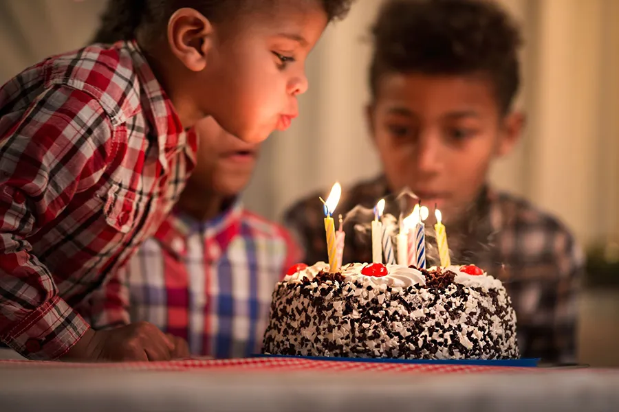 Boy blowing out candles on his birthday cake.