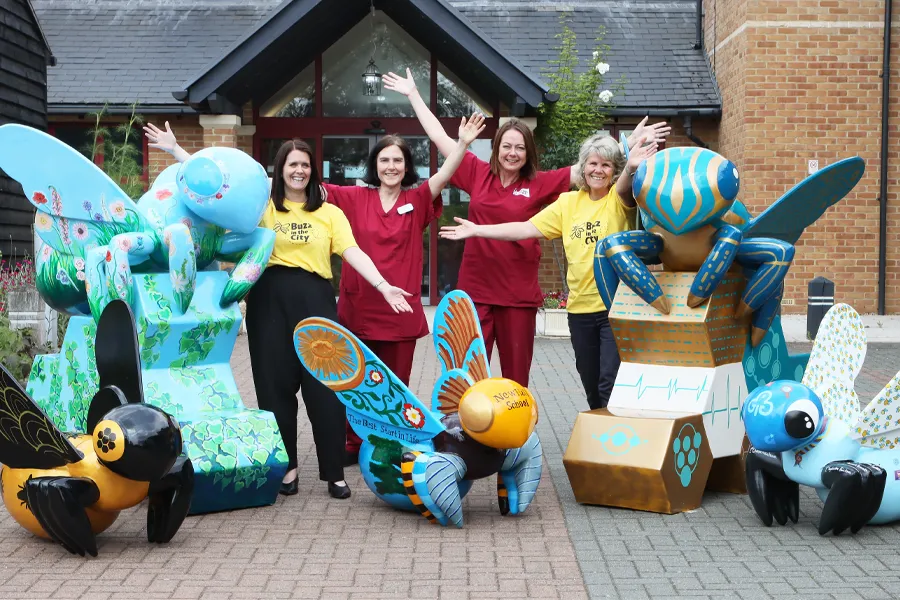 Colourful giant and mini bee sculptures outside Farleigh Hospice with Caroline Smith, Sam Riches, Mandie Barker and Debbie de Boltz from the charity