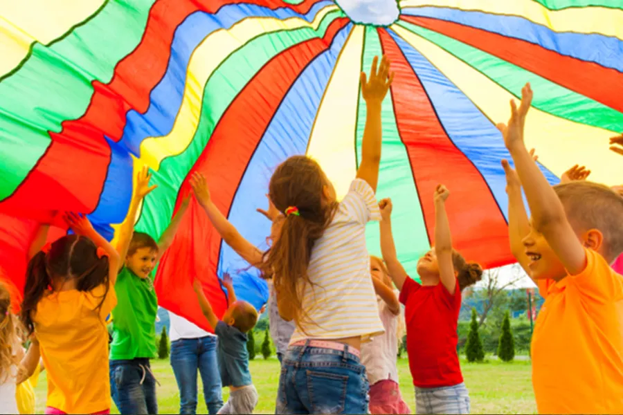 Group of children playing with large multi-coloured parachute
