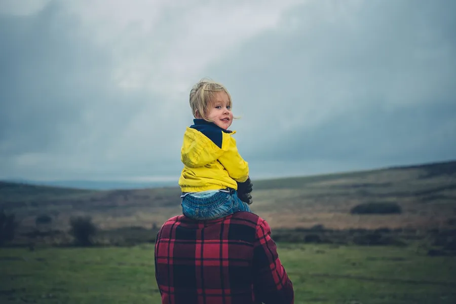 Child on the shoulders of her dad.